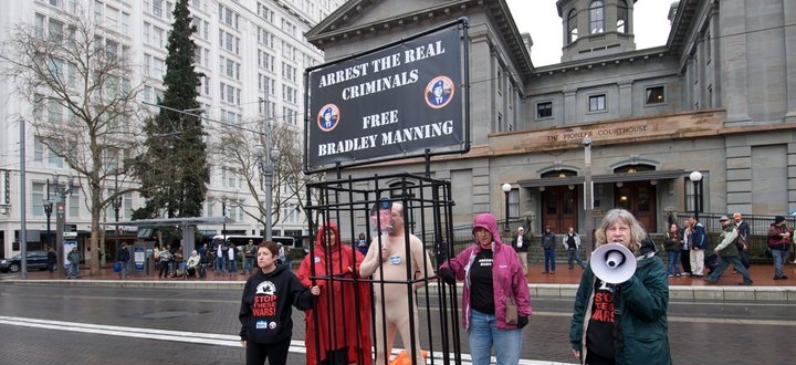 Nude demonstrator as caged Bradley Manning